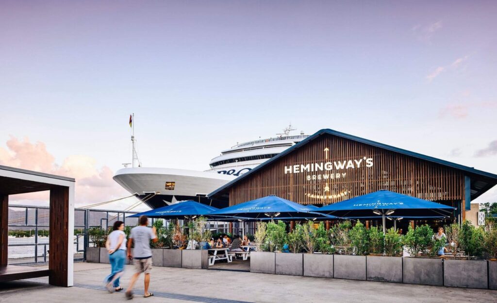 The entrance of Hemingways Brewery with a Cruise ship next to it at sunset.