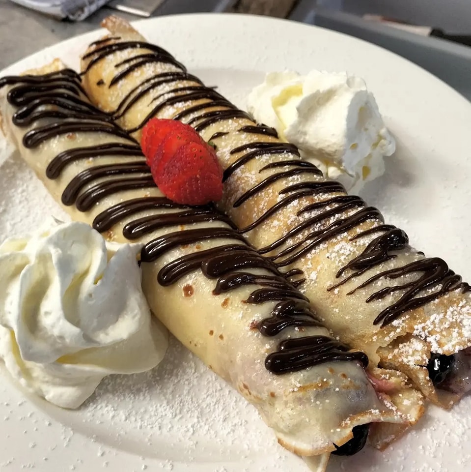 Lillipad Cafe's crapes with chocolate drizzled on top with whipped cream off to the side.