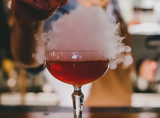 Three Wolves cocktail that has smoke coming from the top of the red cocktail.