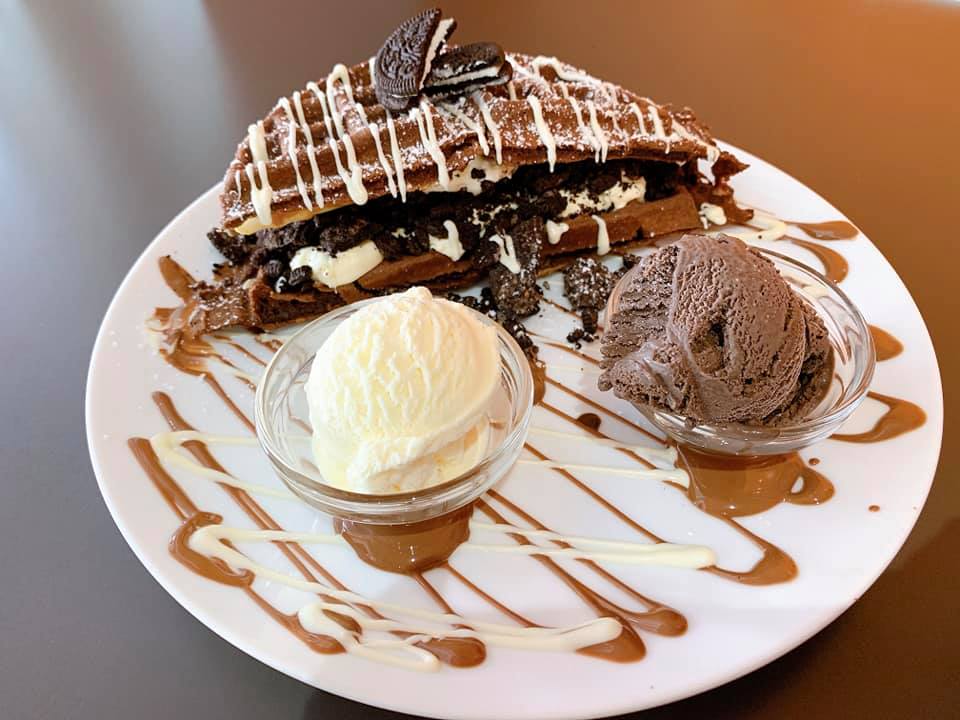 Waffle On's chocolate waffles with carmel drizzled over the plate and a side of ice cream.